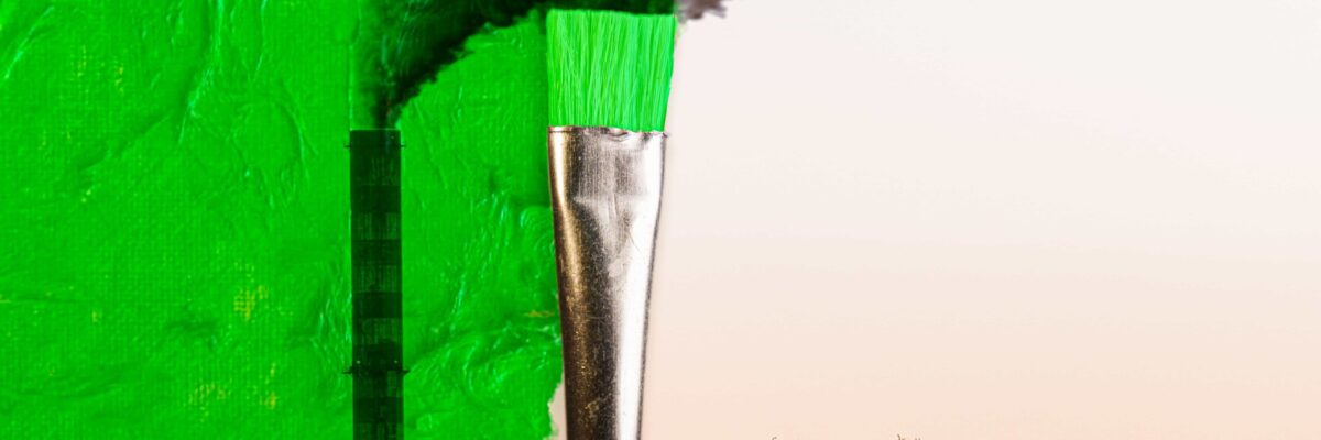Ein schwarzweißes Foto von rauchenden Fabrikgebäuden wird übermalt von einem Pinsel mit grüner Farbe als Symbol für Greenwashing